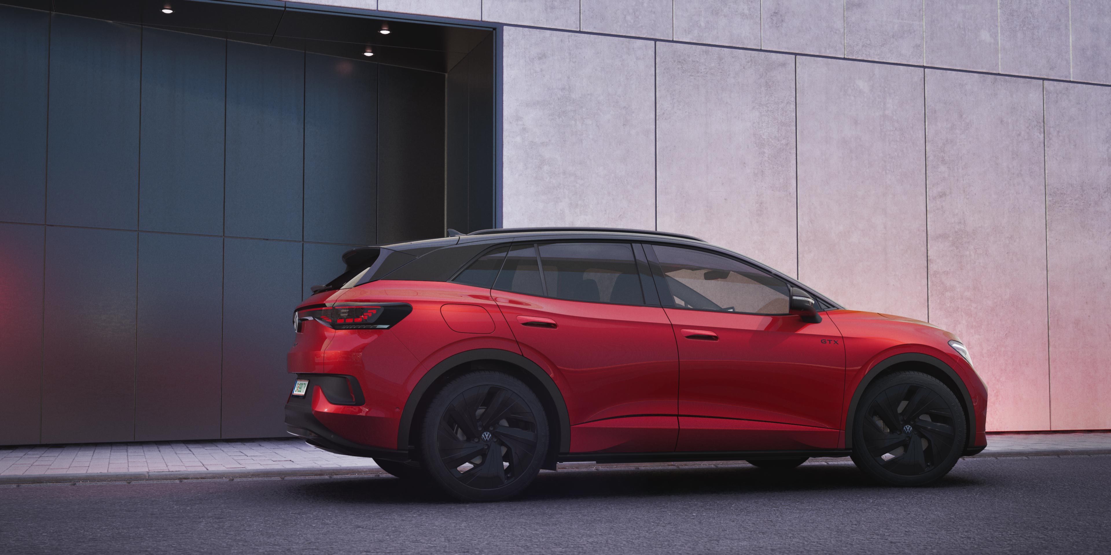 Ein roter VW ID.4 GTX in der schräg seitlichen Heckansicht vor einer schwarz-grauen Hauswand.