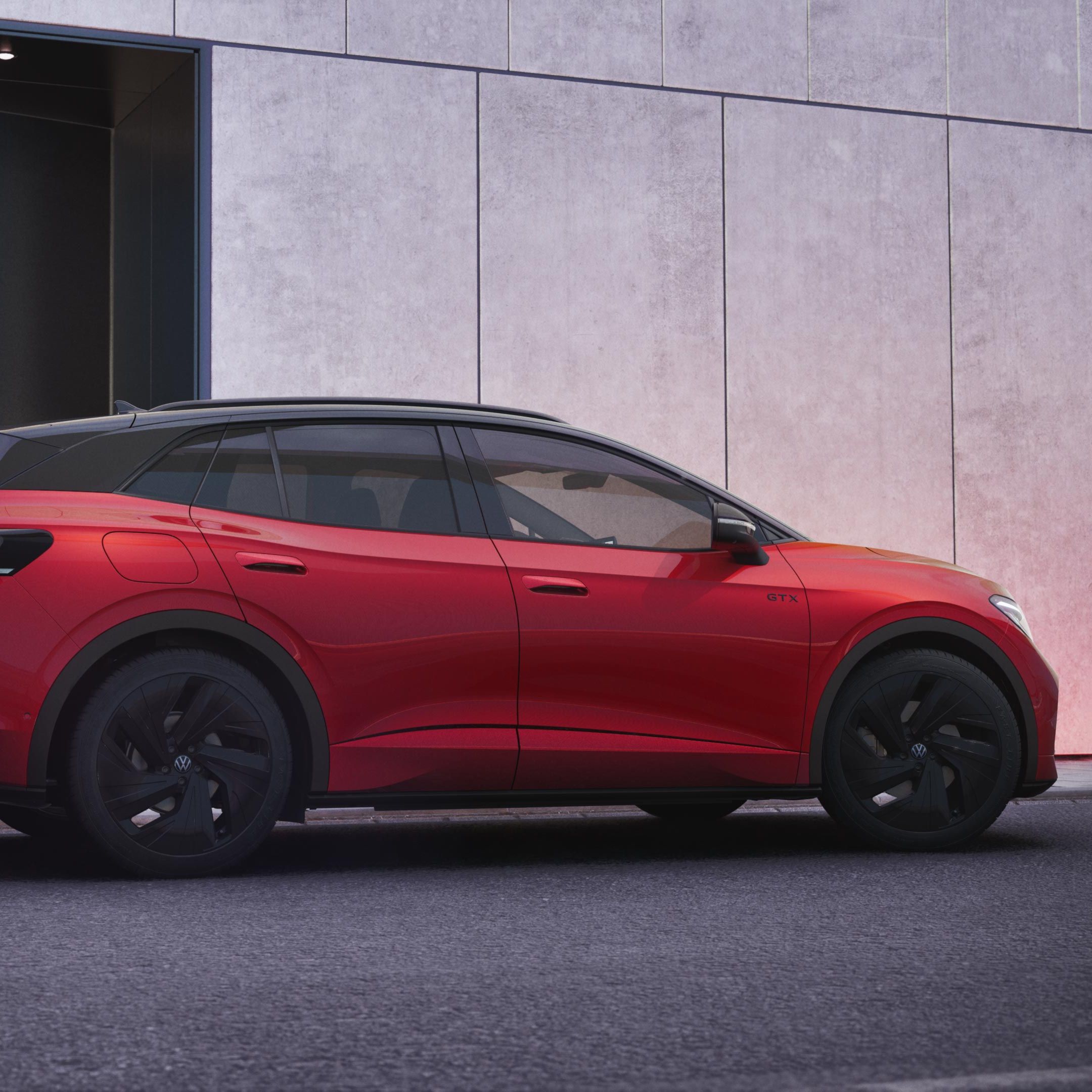 Ein roter VW ID.4 GTX in der schräg seitlichen Heckansicht vor einer schwarz-grauen Hauswand.