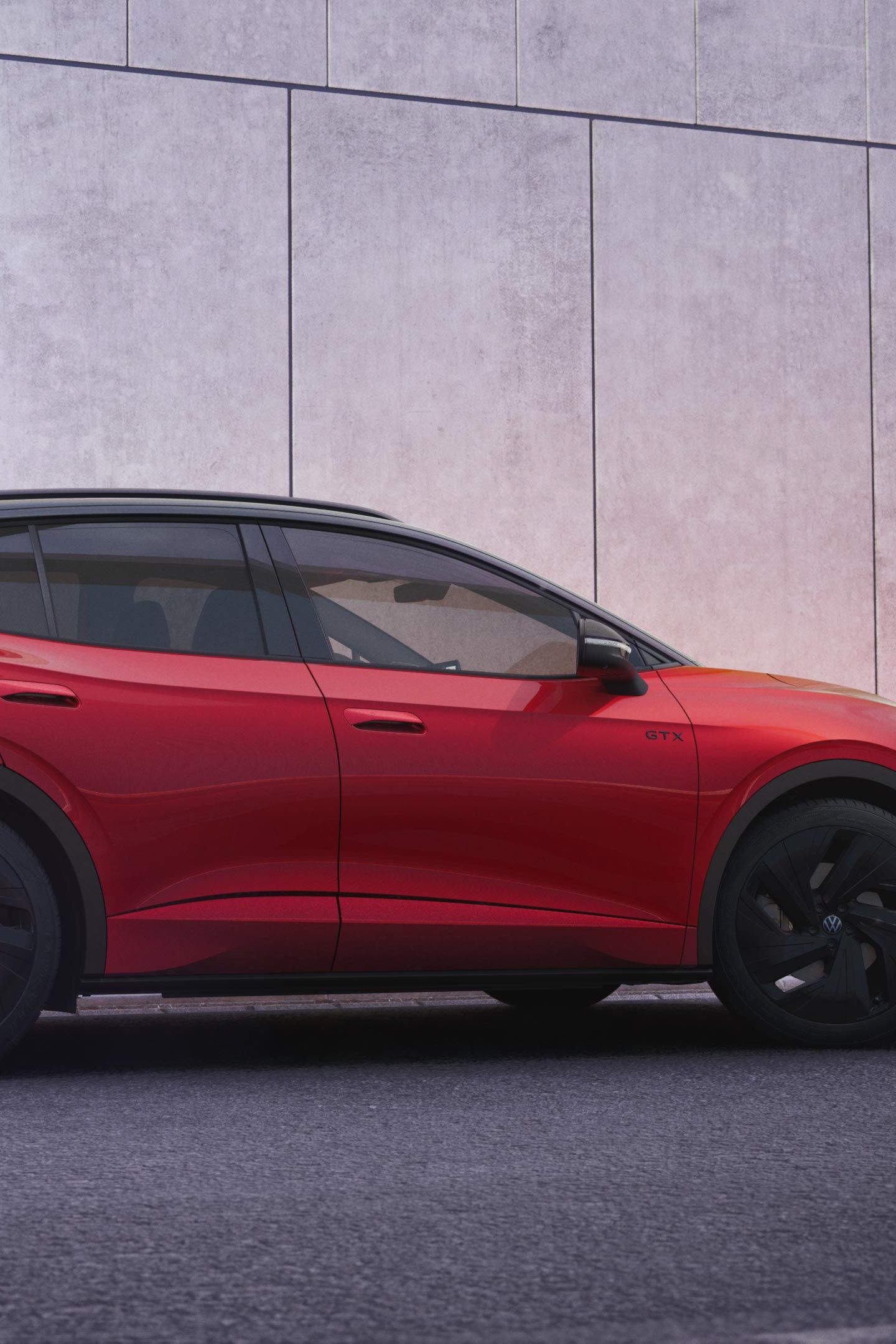 Ein roter VW ID.4 GTX in der schräg seitlichen Heckansicht vor einer schwarz-grauen Hauswand.