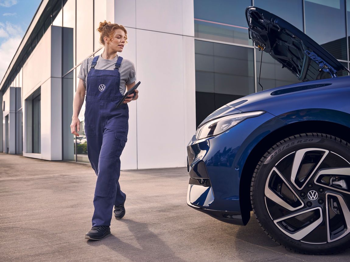 Eine Volkswagen Technikerin mit Tablet begutachtet einen blauen ID.7 