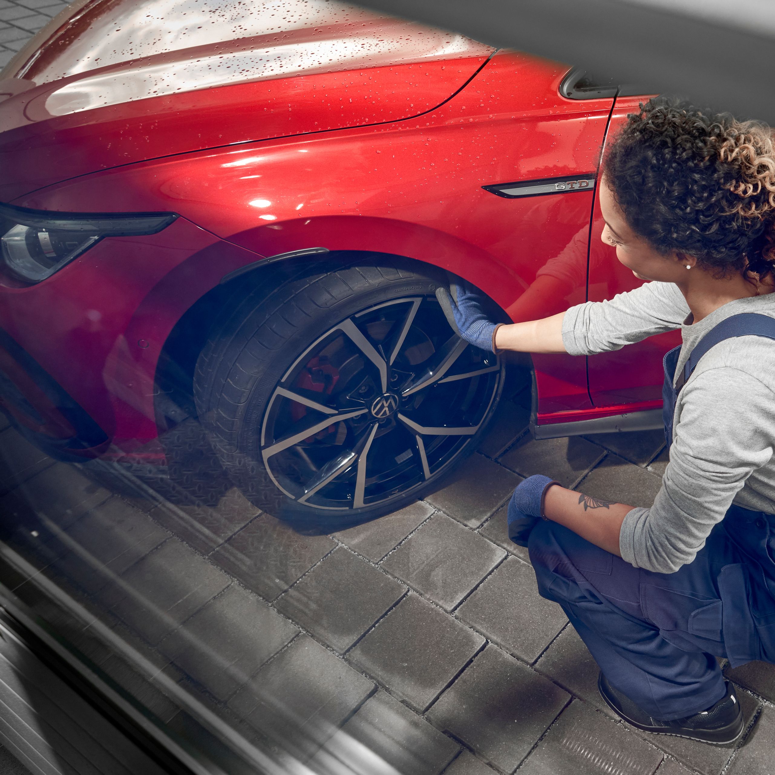 Ženska pregleduje kolo, rdečega VW Golfa.