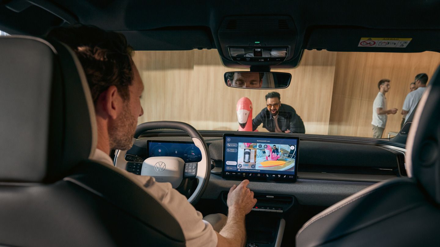 Moški upravlja infozabavni zaslon VW ID. Cross, na zaslonu je prikazan pogled 360° sprednje kamere.