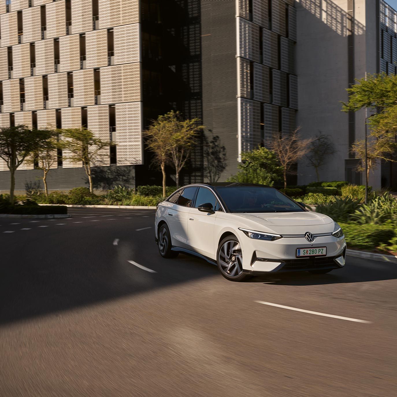 Ein weißer VW ID.7 fährt in einer Kurve in einer Stadt