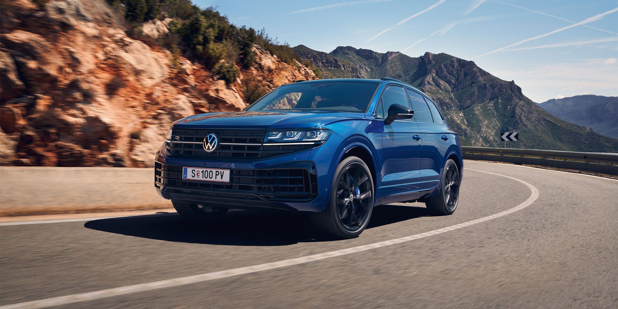 Touareg R eHybrid znamke VWR vozi skozi ovinek, v ozadju gore