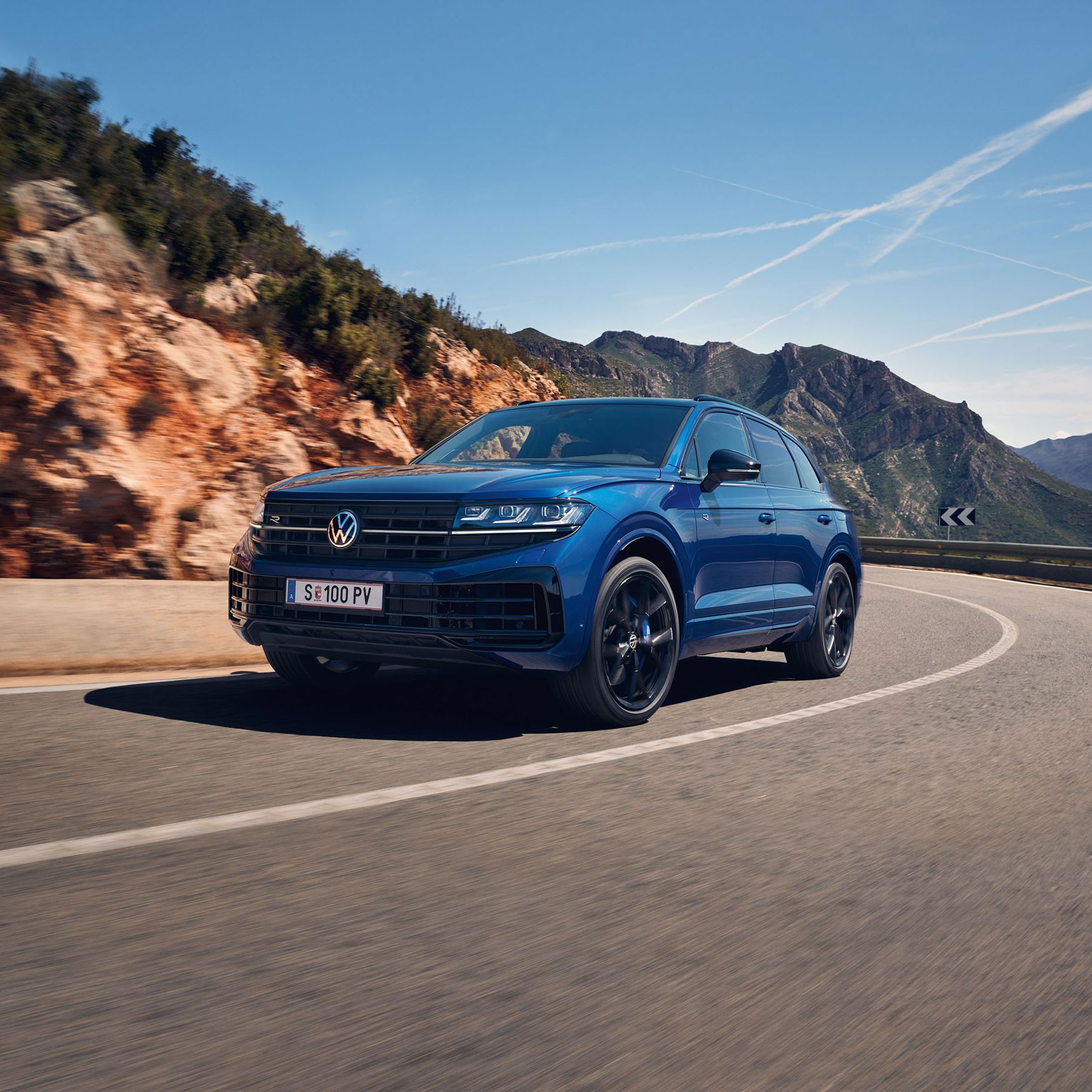 Touareg R eHybrid znamke VWR vozi skozi ovinek, v ozadju gore