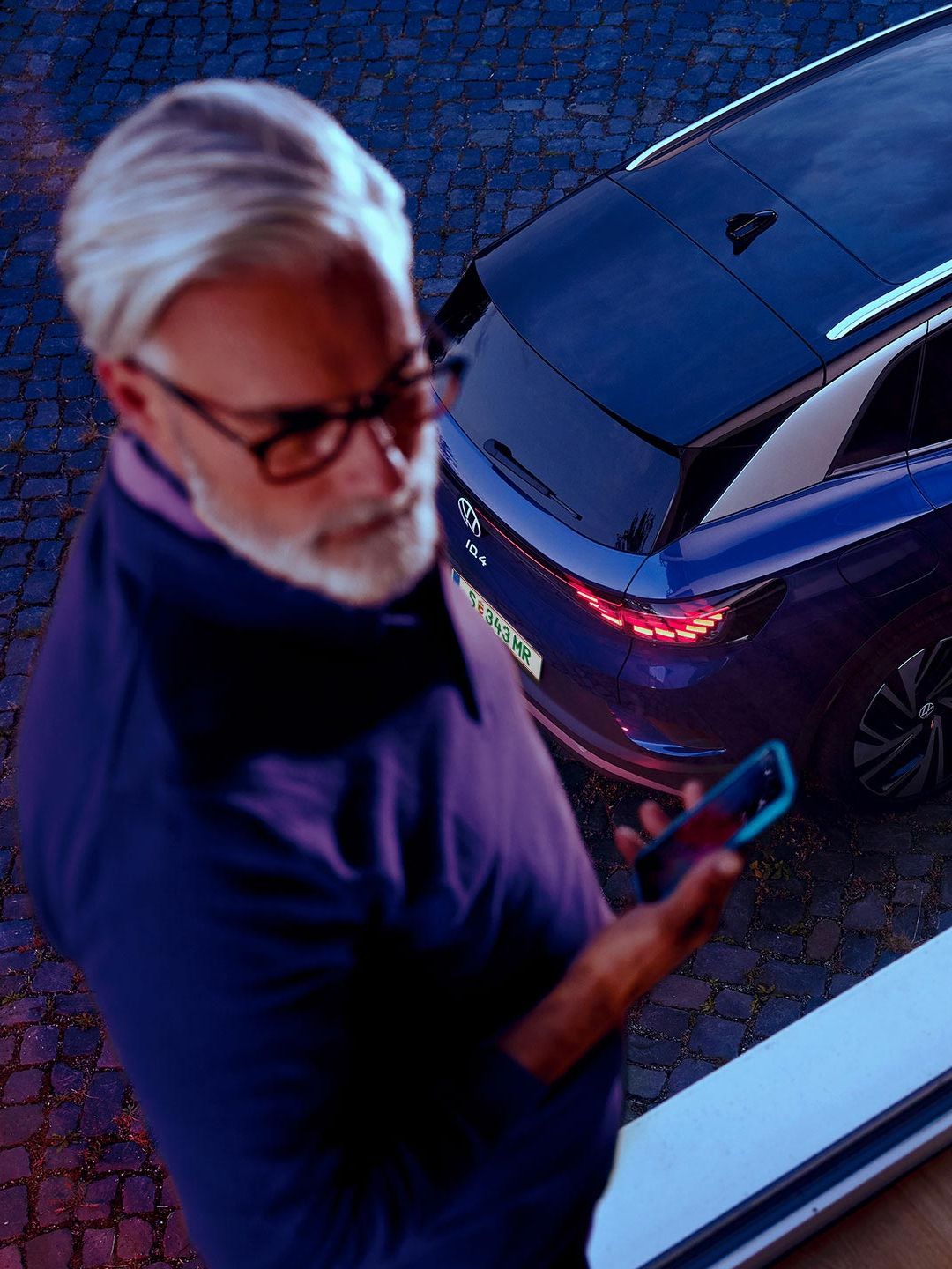 Ein Mann neben einem VW ID.4 in Blau. 