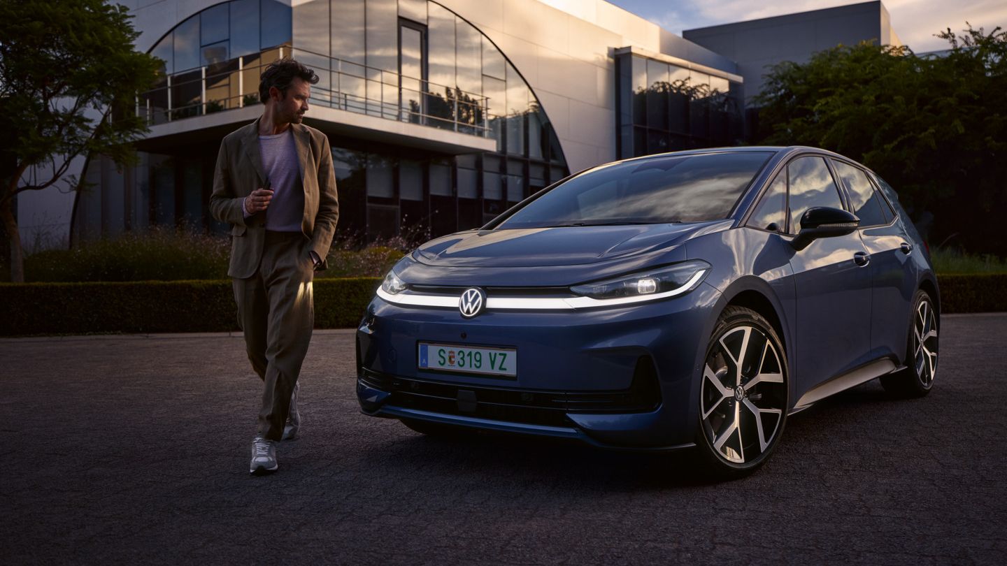 Moški hodi okoli sprednjega dela modrega VW ID.3 Neo in si ogleduje oblikovanje osvetlitve