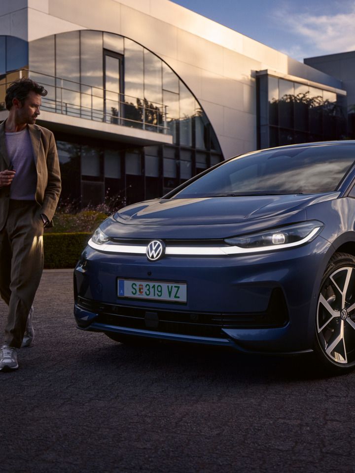 Moški hodi okoli sprednjega dela modrega VW ID.3 Neo in si ogleduje oblikovanje osvetlitve