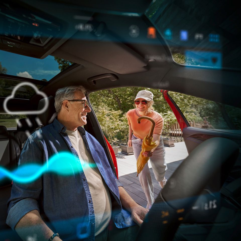 POV HMI: Frau reicht Mann einen Regenschirm, während er auf dem Fahrersitz eines Tiguan sitzt