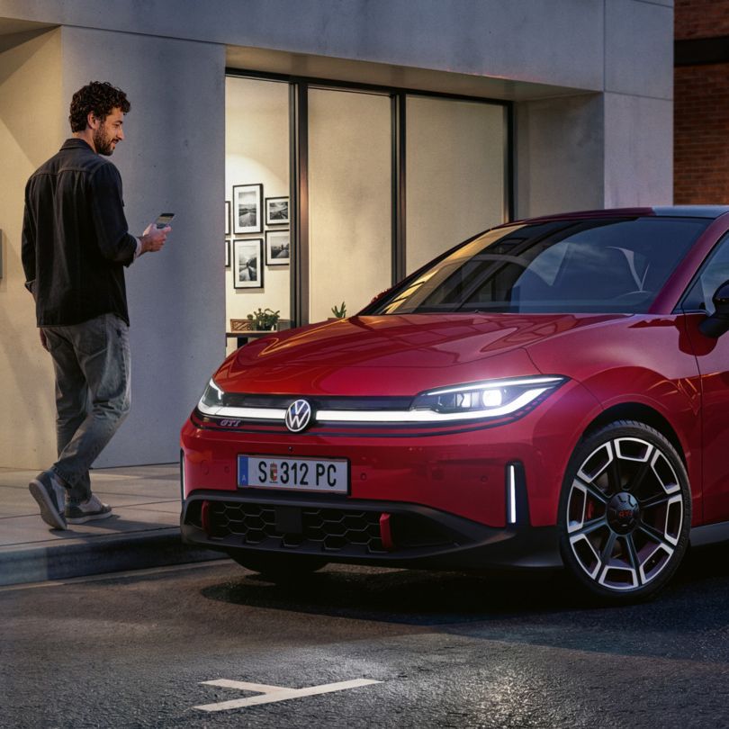 Oseba gre mimo rdečega VW ID-ja. Polo GTI, parkiranega pred sodobno stavbo.