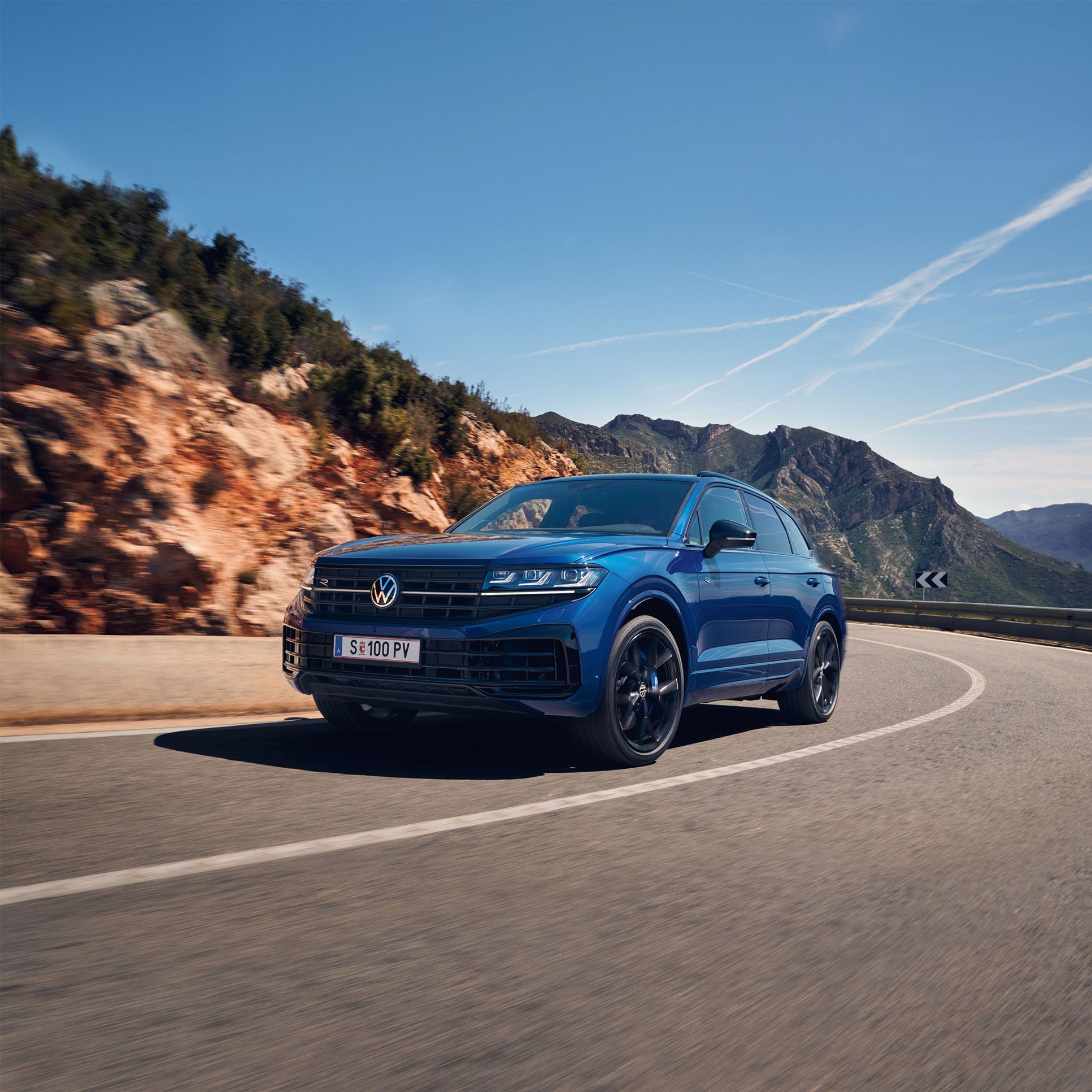 Touareg R eHybrid znamke VWR vozi skozi ovinek, v ozadju gore