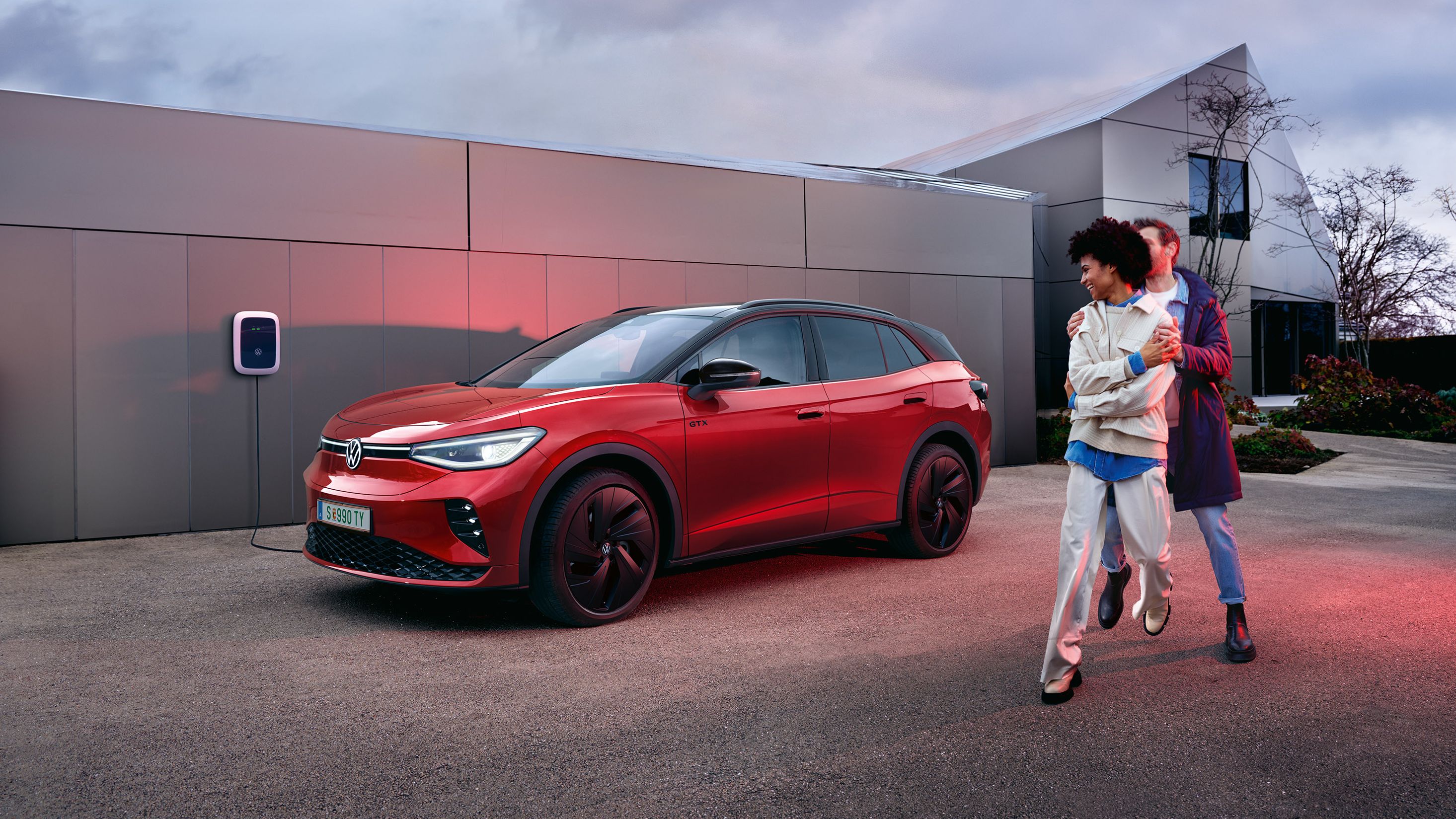 Zwei Personen stehen neben einem roten VW ID.4