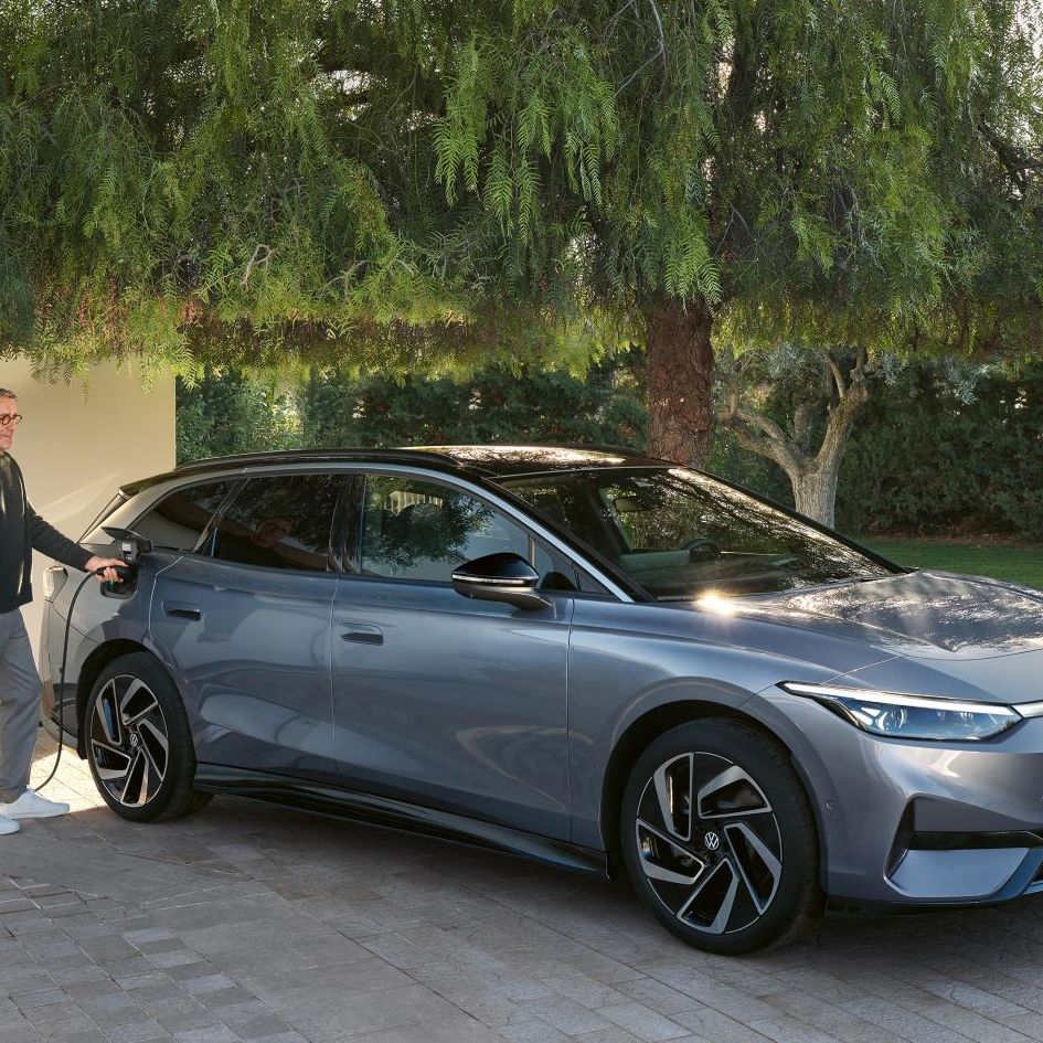  Moški stoji pred stensko polnilno postajo in polni svoj VW ID. 7 Tourer.