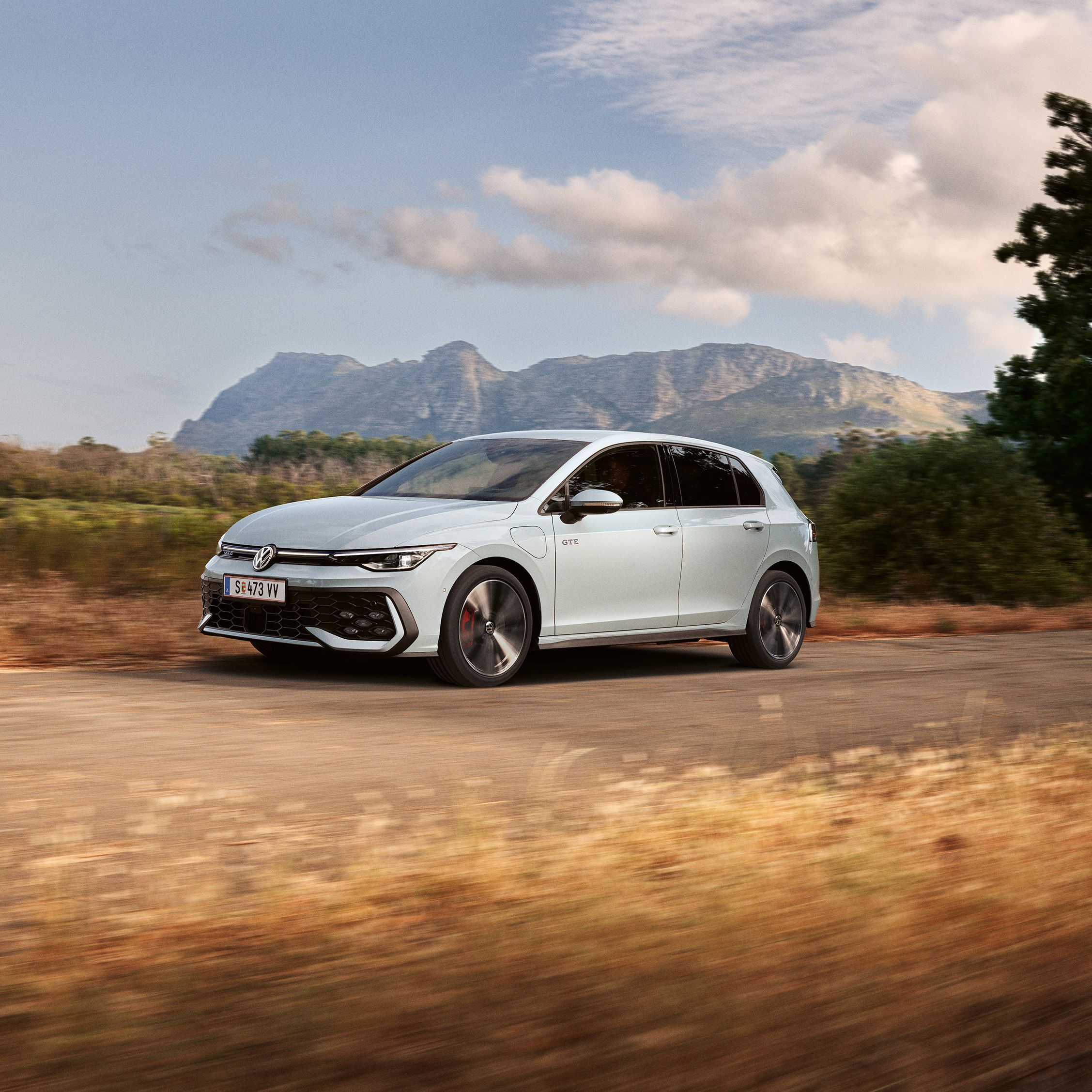 Der VW Golf GTE fährt auf einer Landstraße, im Hintergrund sieht man Berge