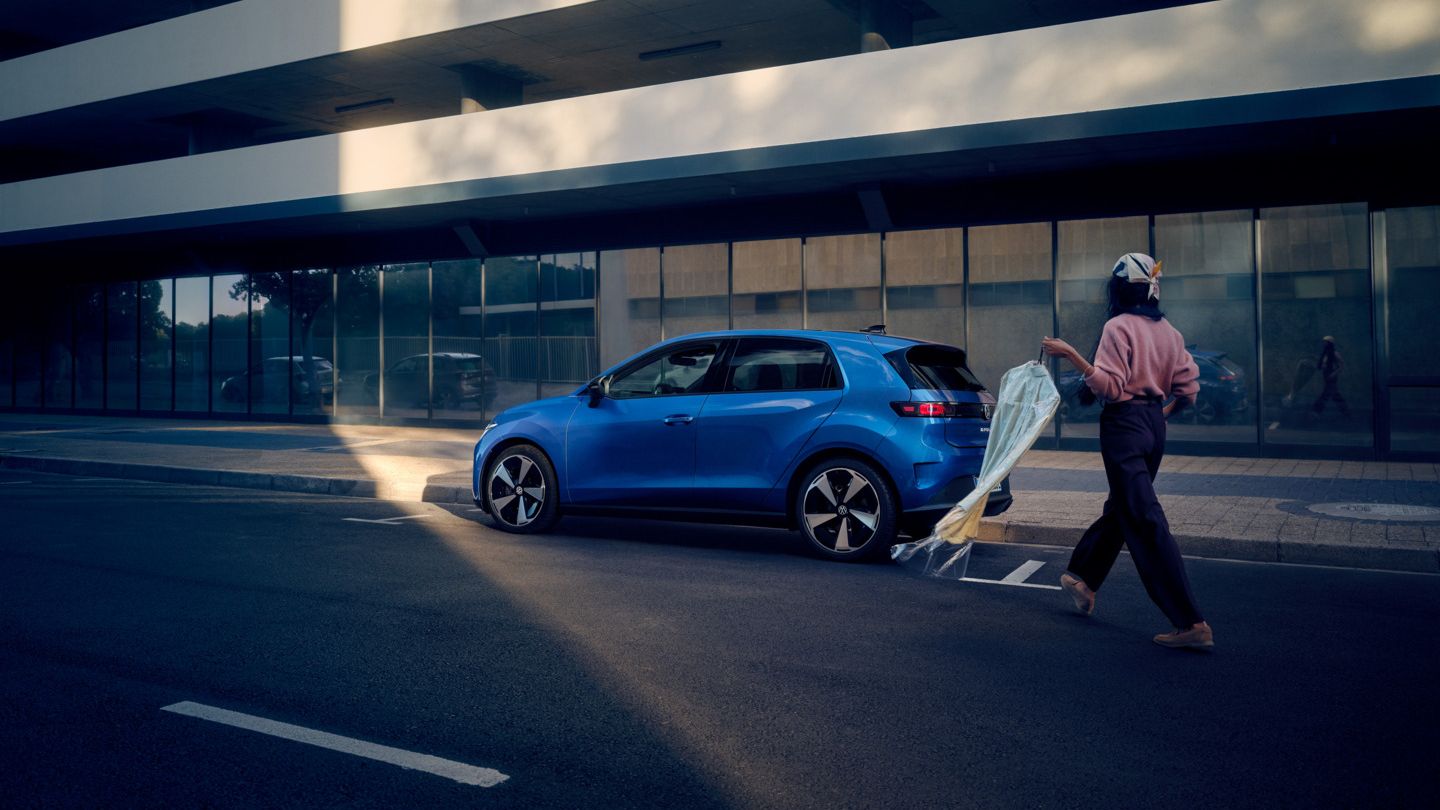 Moder VW ID. Polo Style je parkiran ob cesti, ženska se približa vozilu.