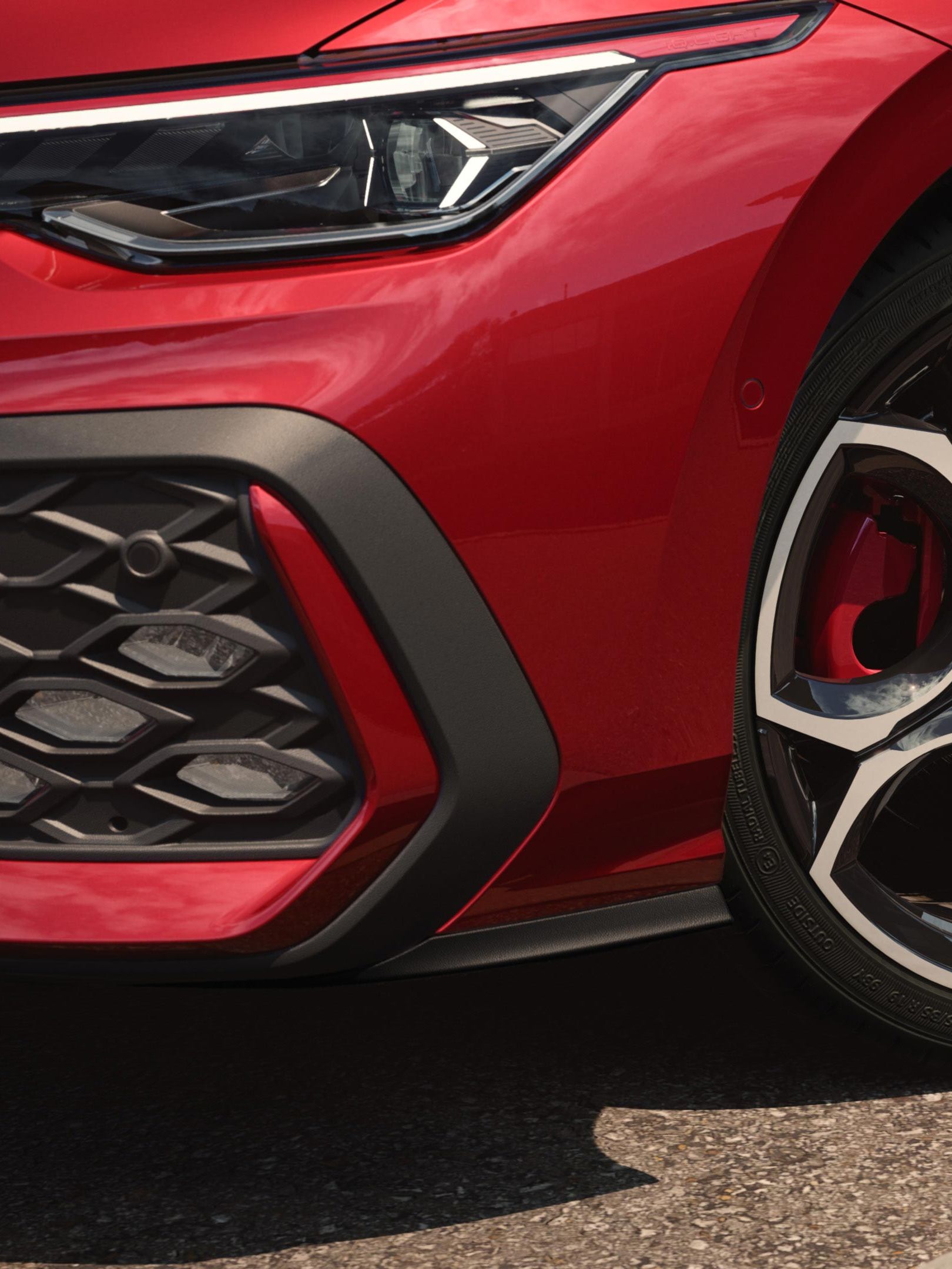 Bližnji posnetek platišča pri rdečem VW Golfu GTI.