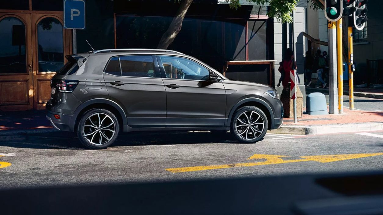 VW T-Cross z opcijskim dizajn paketom "Schwarz" je parkiran na ulici. Avtomobil ima črni ohišji zunanjih ogledal in zatemnjena stekla od B-stebričkov naprej.