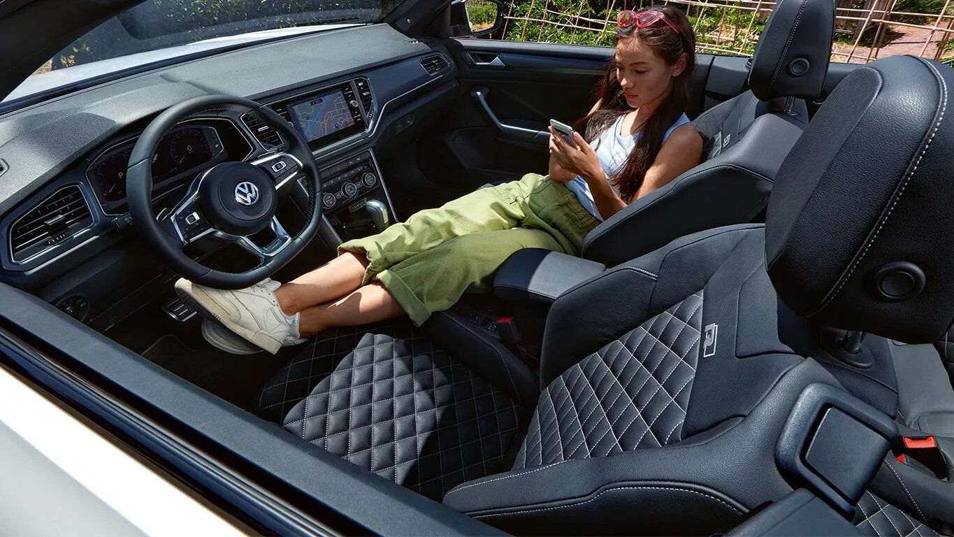 Ženska sedi v T-Rocu Cabriolet in gleda v mobilni telefon