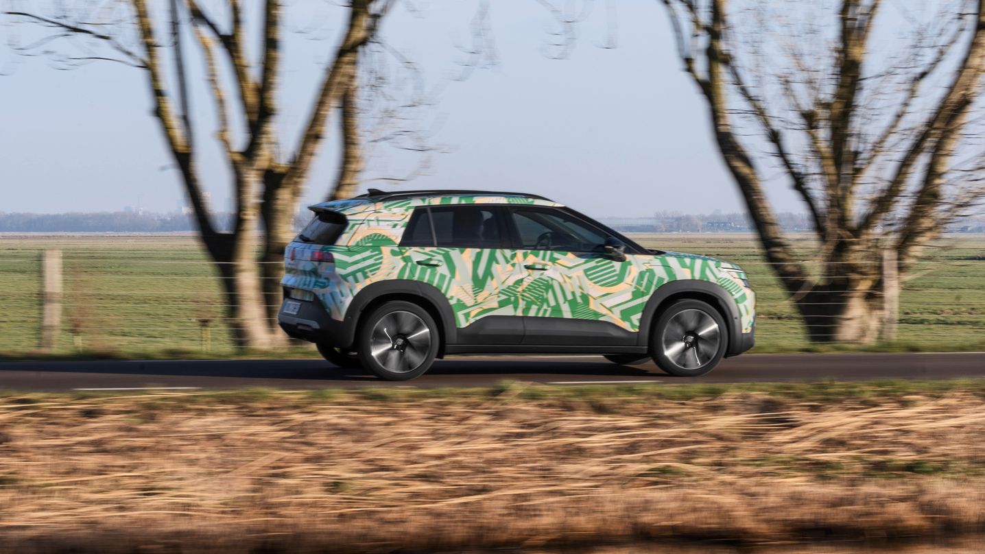 VW ID. Cross z maskirno folijo je od strani prikazan med vožnjo po regionalni cesti.
