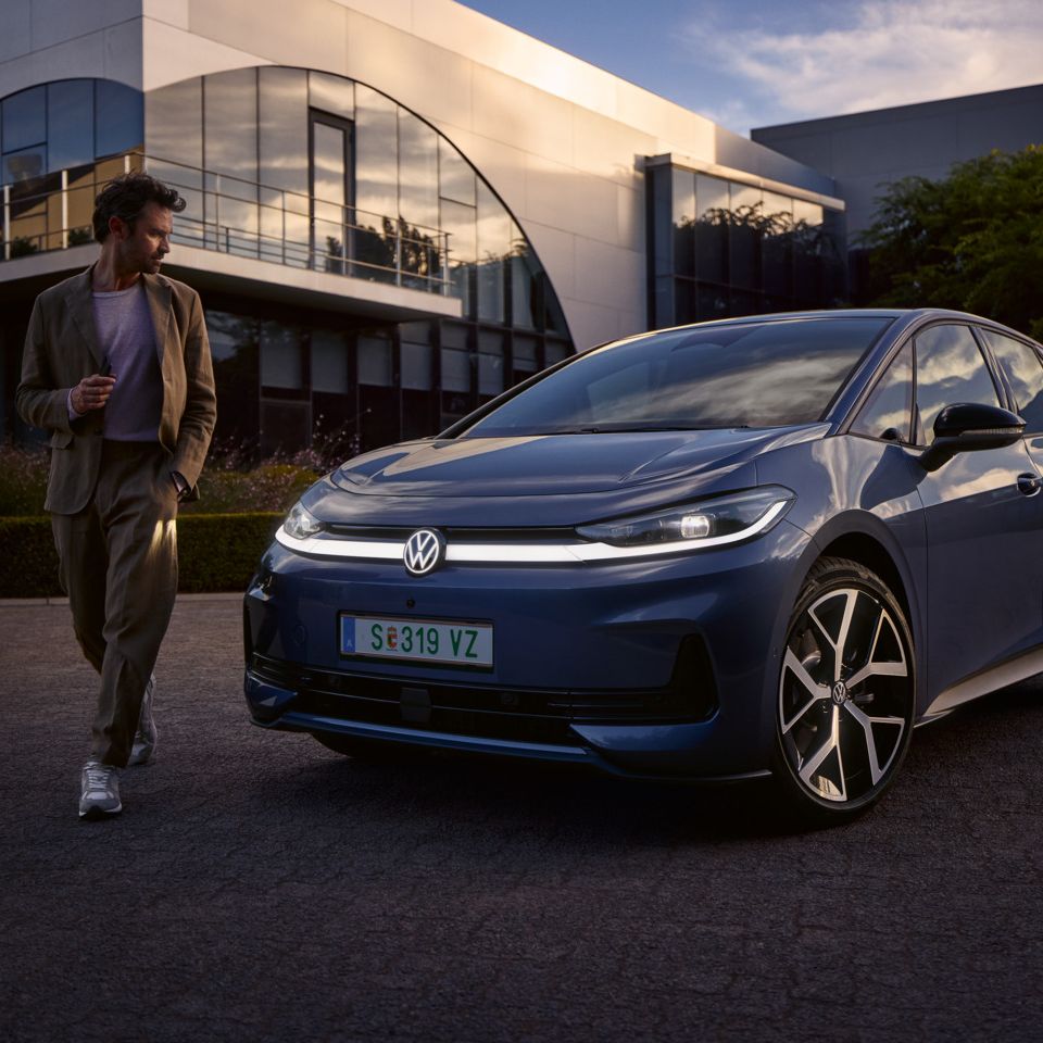 Moški hodi okoli sprednjega dela modrega VW ID.3 Neo in si ogleduje oblikovanje osvetlitve