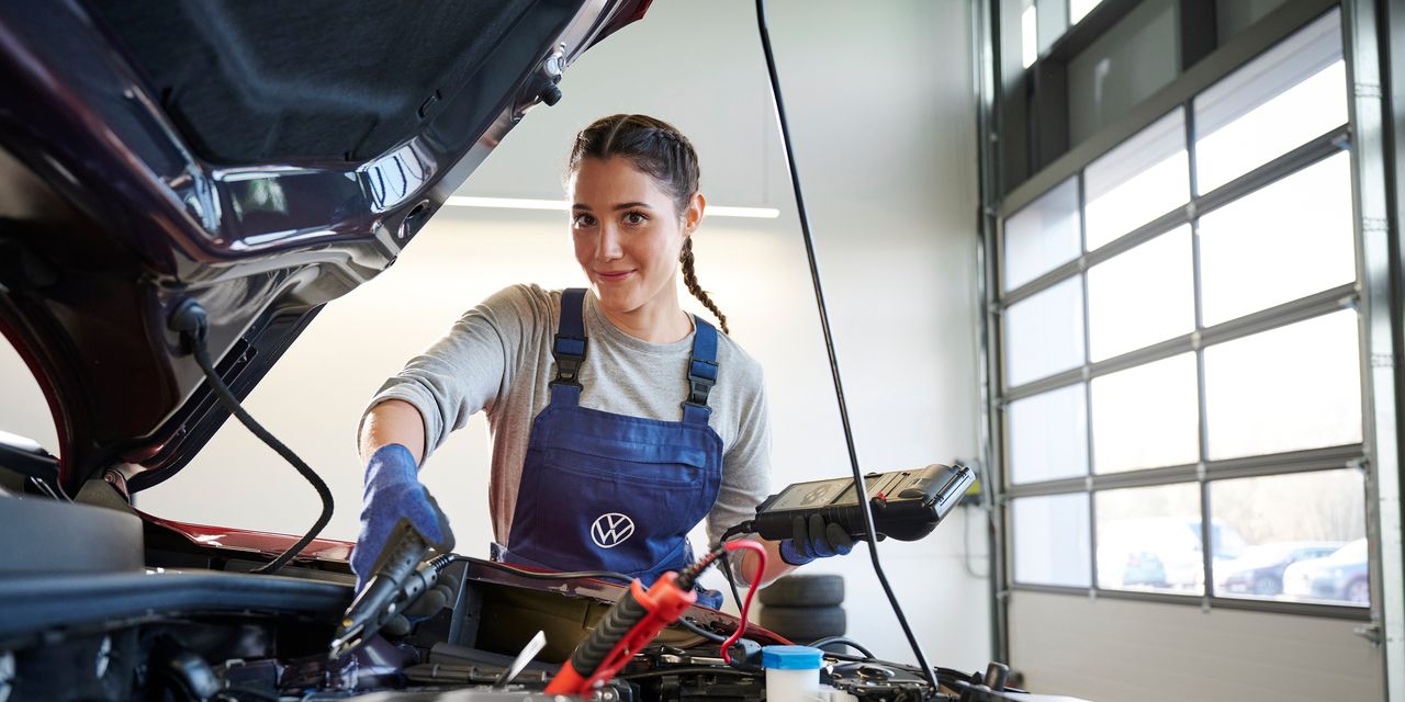 Eine Volkswagen Mechanikerin überprüft die Batterie eines Volkswagen