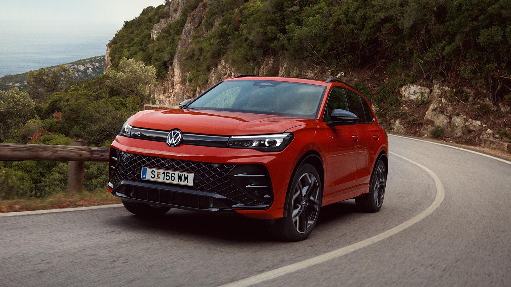 Rdeči VW Tiguan, ki vozi po ovinkasti cesti.
