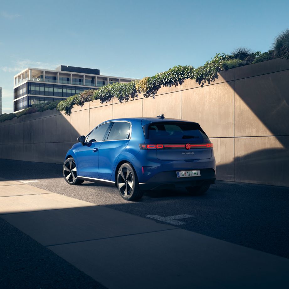 Modri VW ID. Polo Style stoji ob cesti pred zeleno steno.