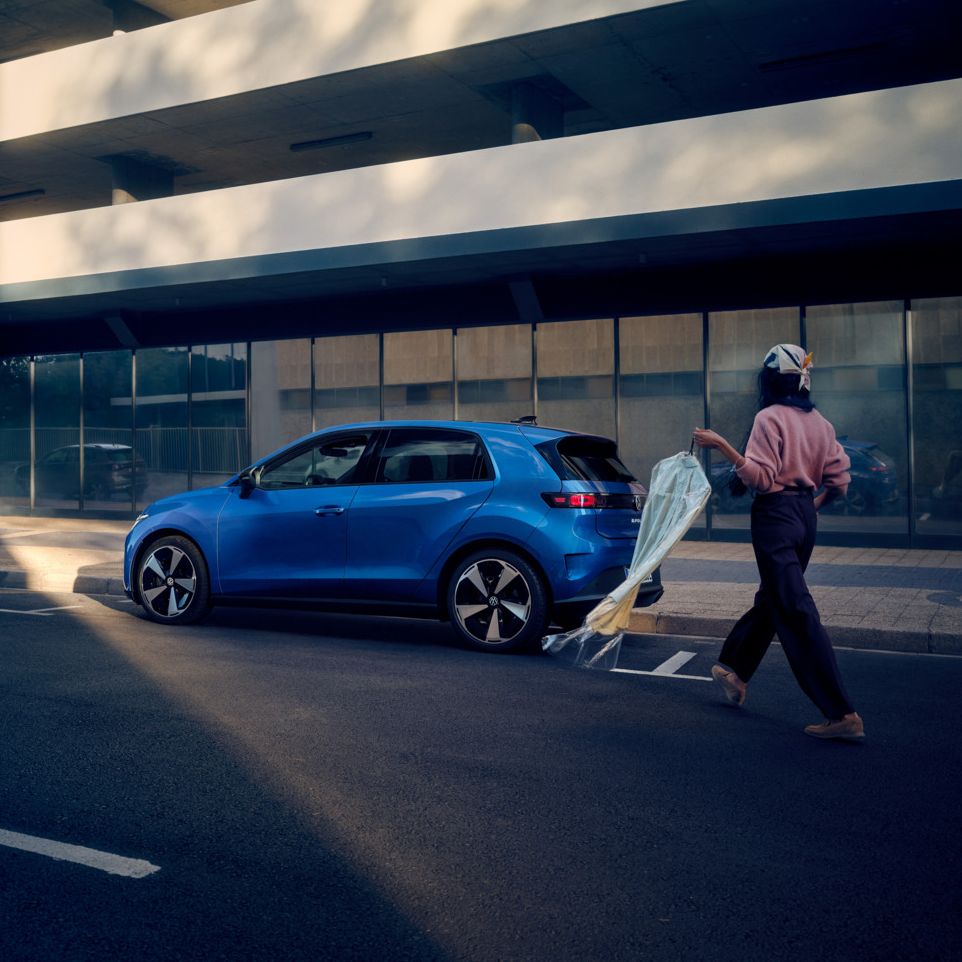 Moder VW ID. Polo Style je parkiran ob cesti, ženska se približa vozilu.