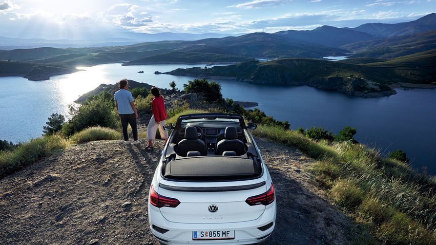 VW T-Roc Cabriolet pred čudovitim razgledom, par stoji poleg avtomobila