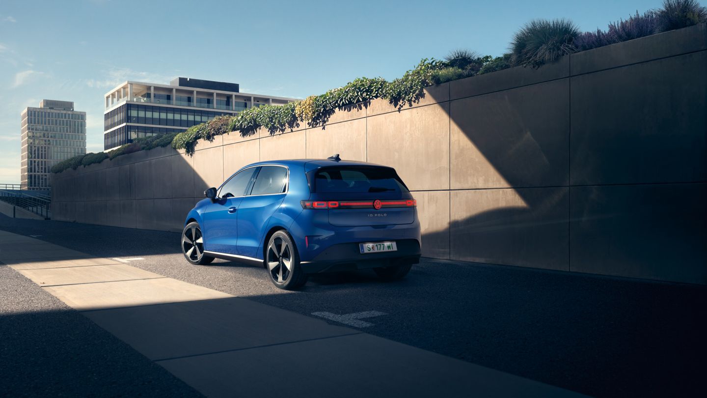 Modri VW ID. Polo Style stoji ob cesti pred zeleno steno.