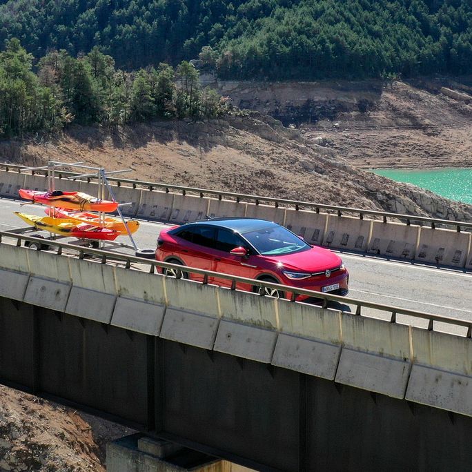 Ein roter ID.5 GTX fährt mit einem Anhänger über eine Brücke