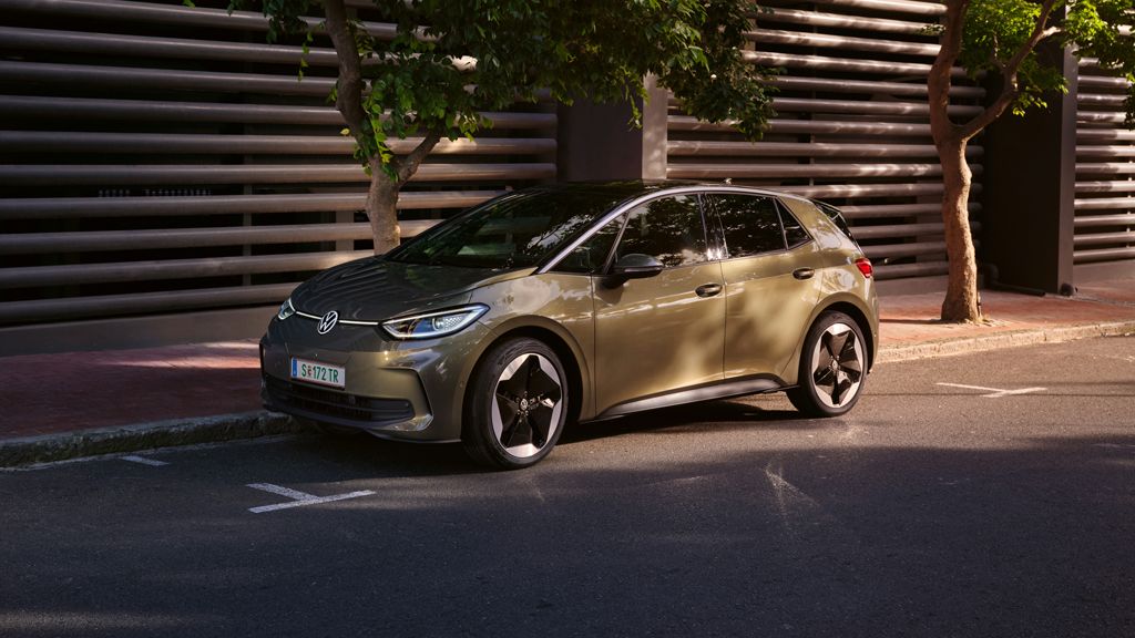 Slika prikazuje VW ID.3 v temni olivinsko zeleni kovinski barvi s platišči Sanya. Avtomobil je bočno parkiran ob robniku. 