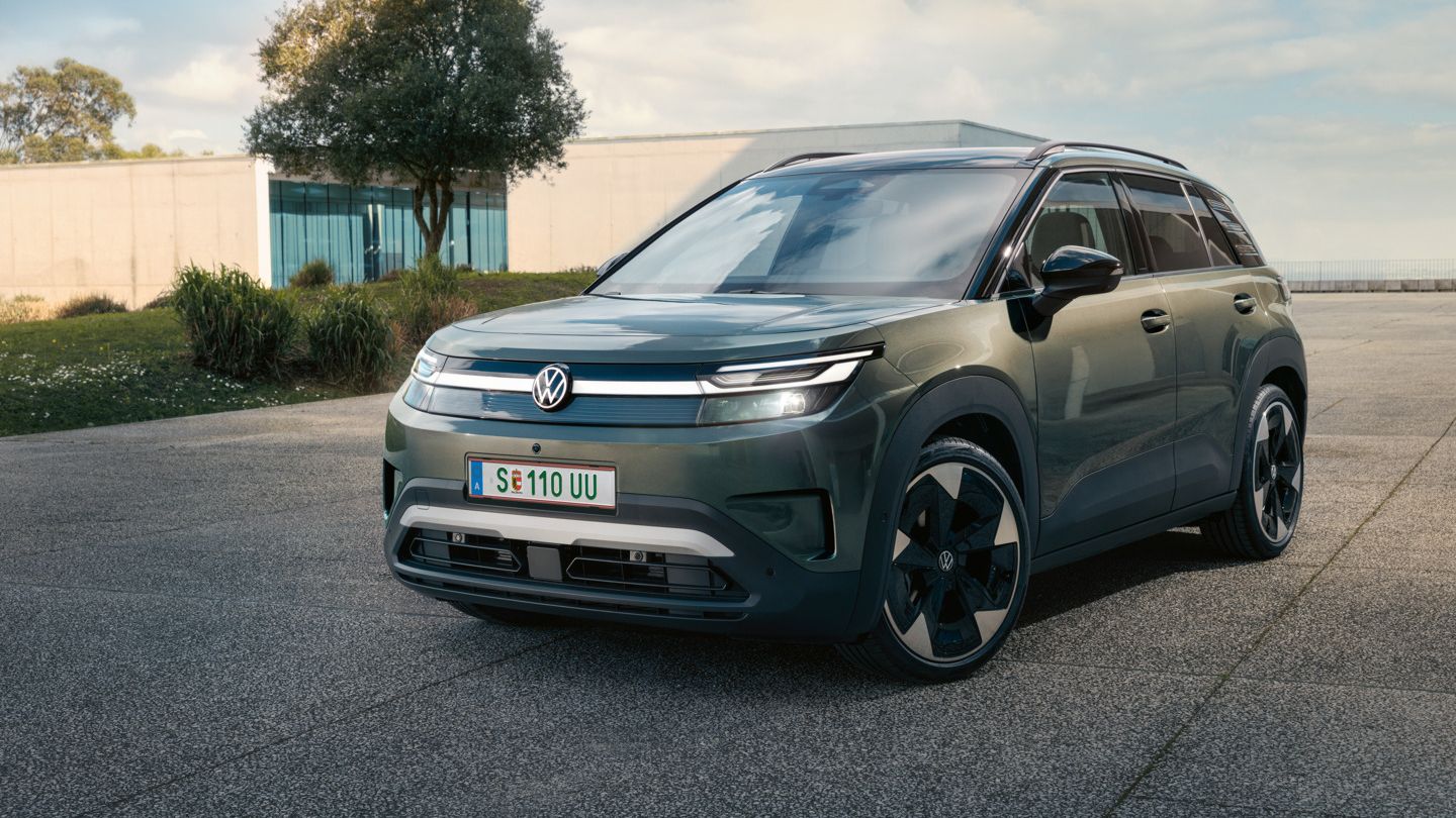 Zelen VW ID. Cross stoji na betonski površini pred sodobno stekleno stavbo.