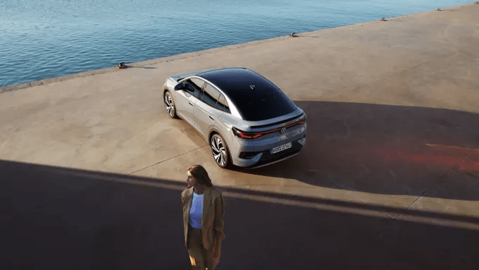 Zadek modela VW ID.5 je od zgoraj s strani prikazan na nabrežju pristanišča. V ospredju stoji ženska.