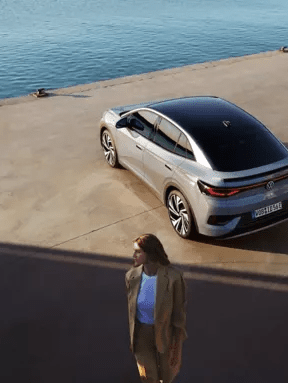 Zadek modela VW ID.5 je od zgoraj s strani prikazan na nabrežju pristanišča. V ospredju stoji ženska.