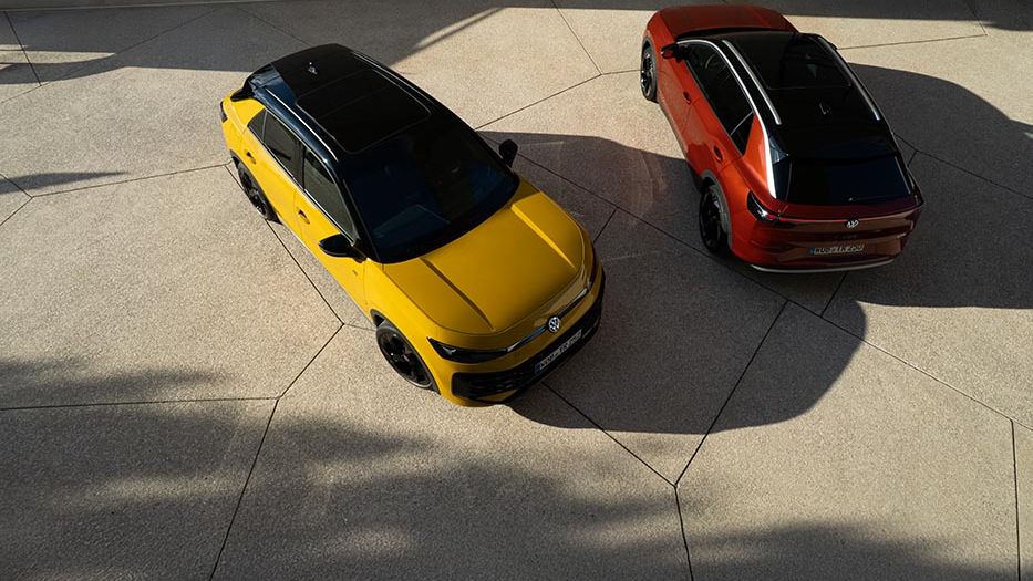 Rumeni VW T-Roc R-Line in rdeči VW T-Roc Style sta slikana od zgoraj zraven moderne stavbe.