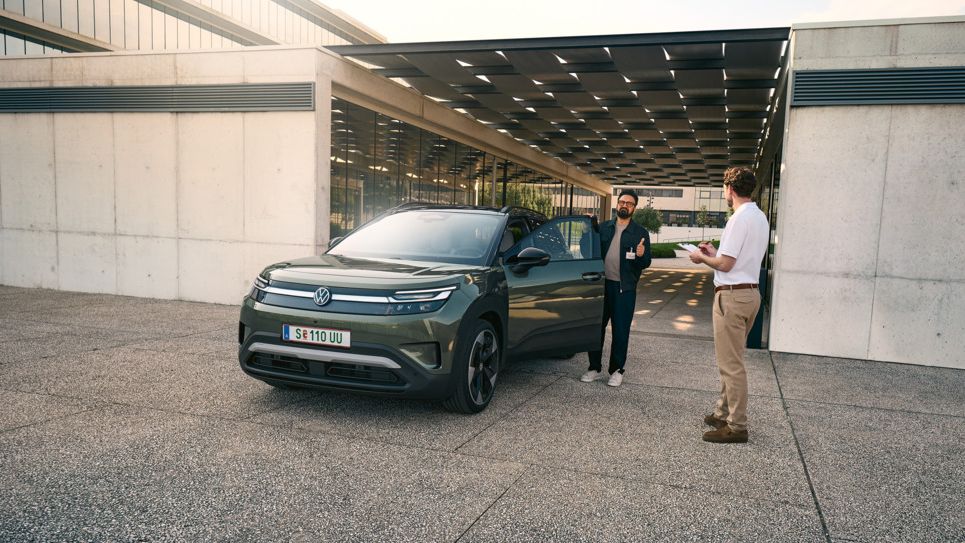 Moški se usede v VW ID. Crossa in se pogovarja z inženirjem z registratorjem v roki.
