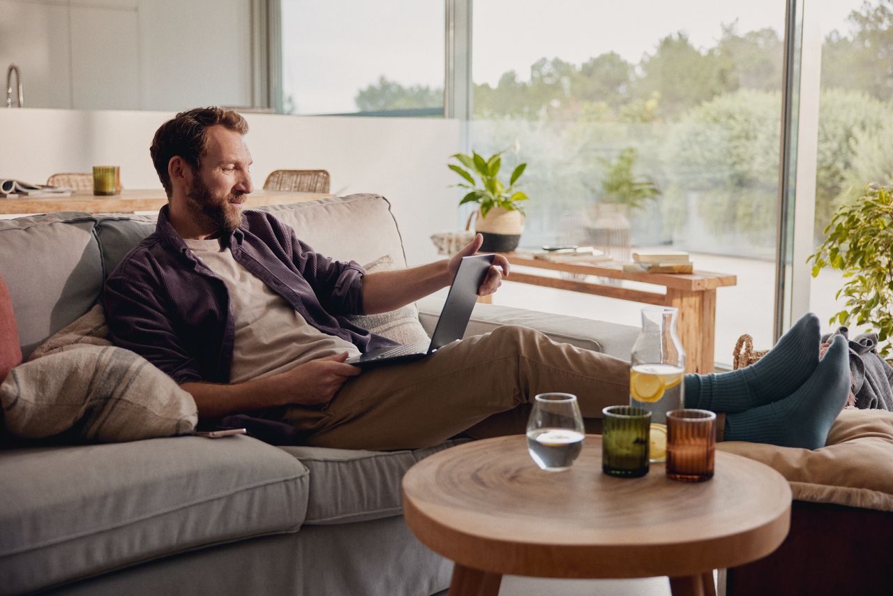 Moški, ki sedi doma in gleda tablični računalnik