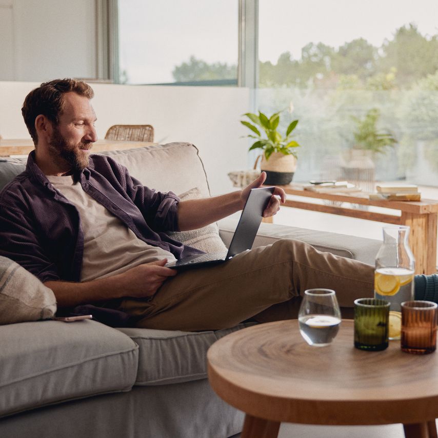 Mann sitzt zu Hause und schaut auf ein Tablet