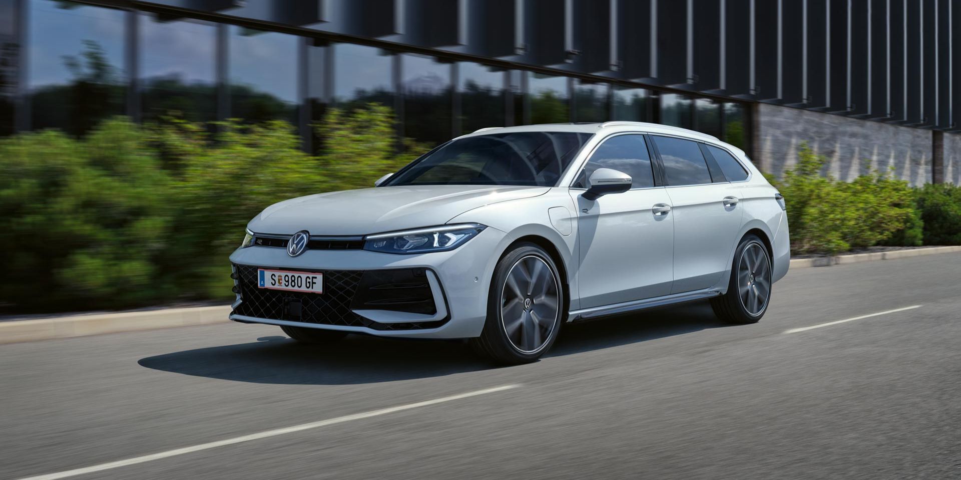 Bel VW Passat je parkiran bočno pred stavbo.