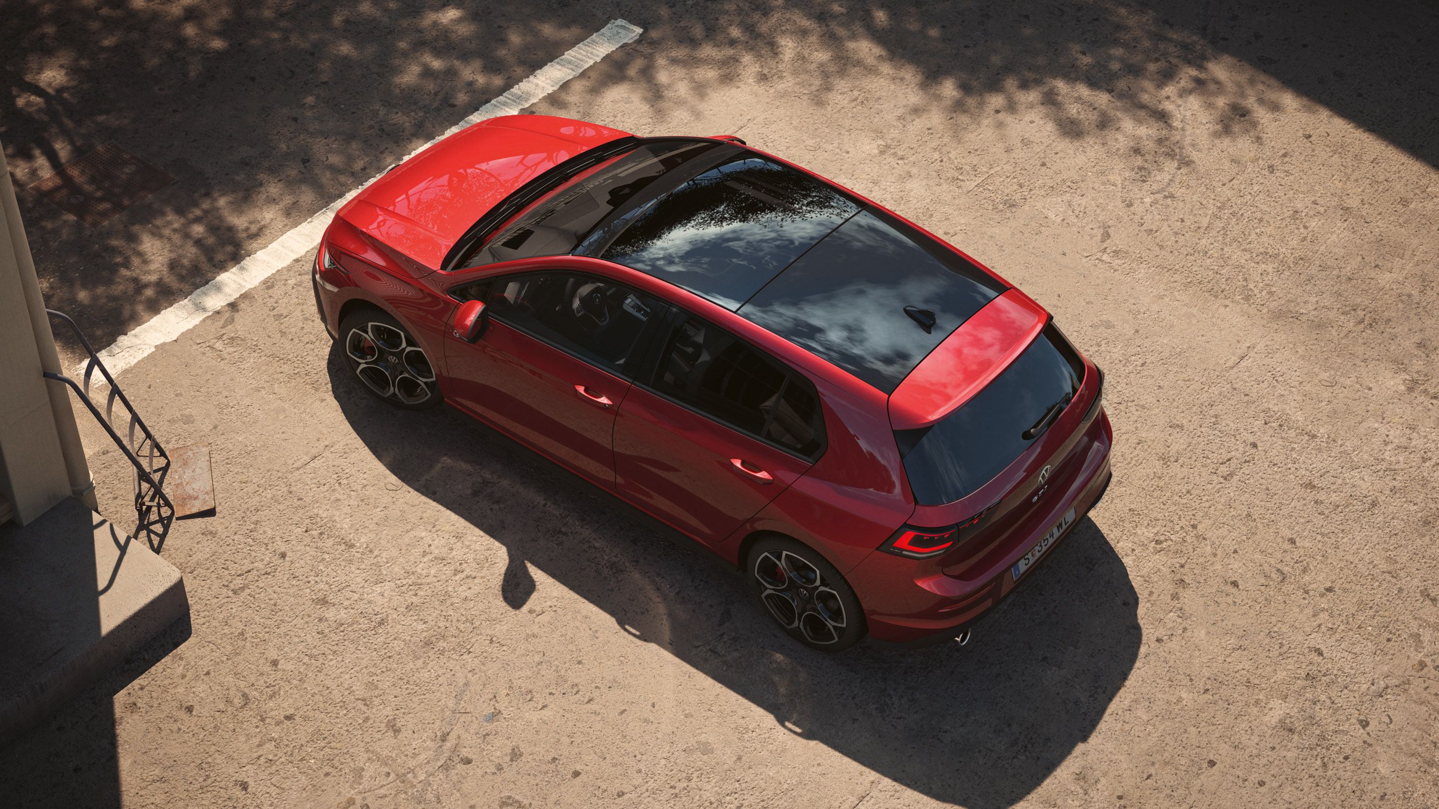 Od zgoraj je prikazan rdeč VW Golf, v središču posnetka je panoramsko dvižno-pomično strešno okno.