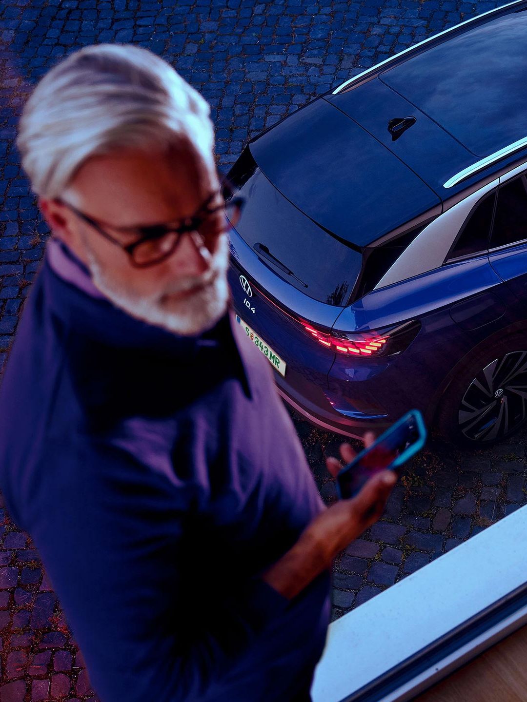 Ein Mann neben einem VW ID.4 in Blau. 