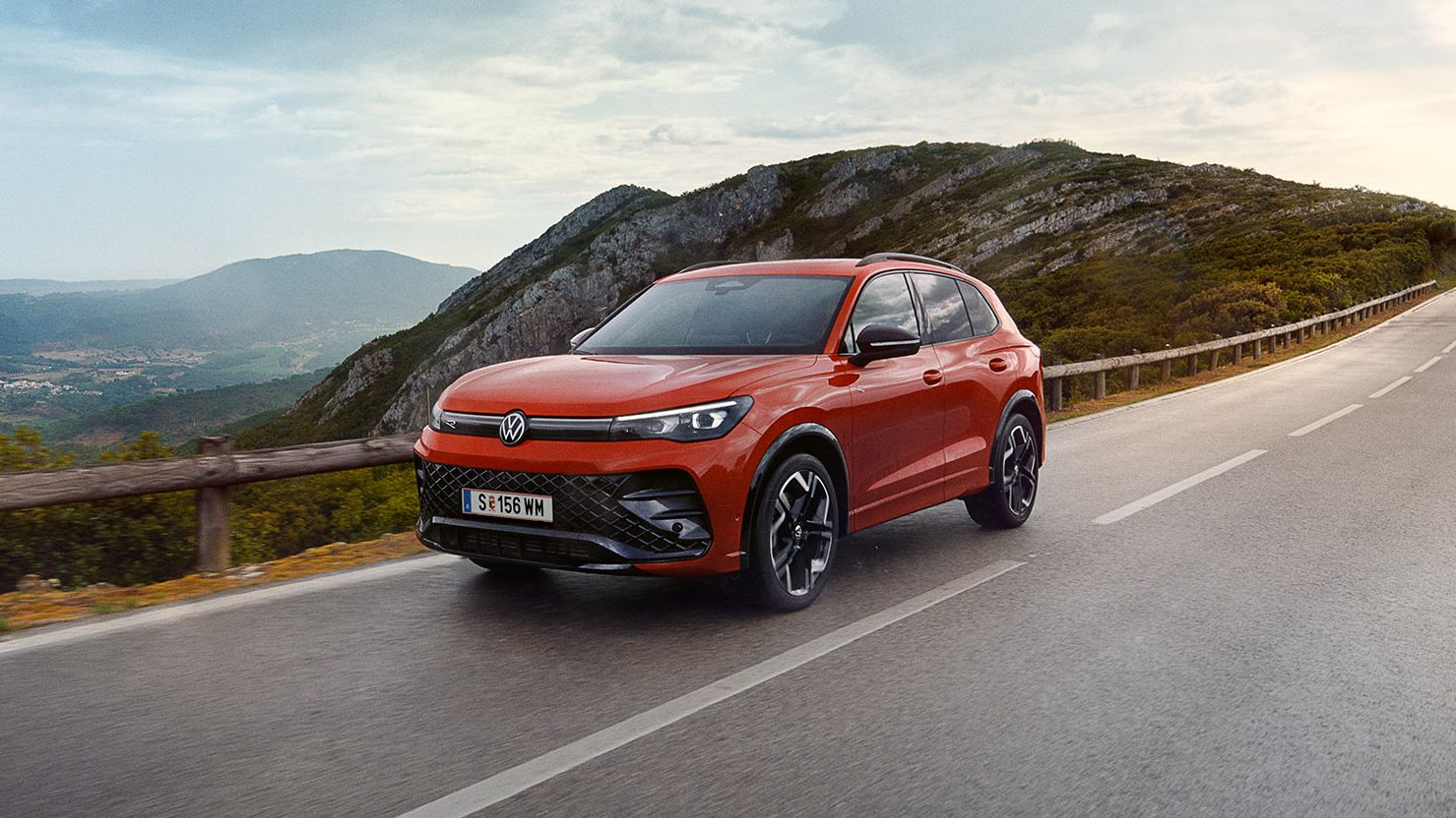 Rdeč VW Tiguan vozi po cesti.
