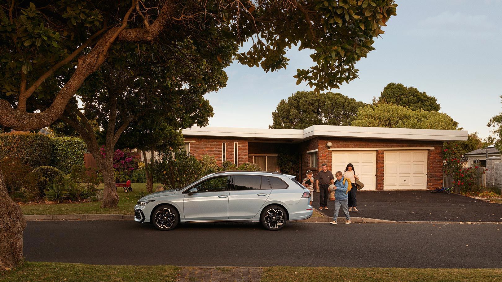 Seitenansicht eines VW Golf Variant in der Farbe Ice Blue Metallic geparkt vor Einfamilienhaus