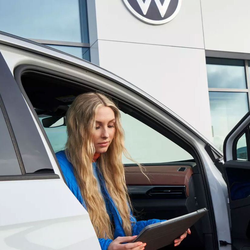 Eine Frau sitzt bei geöffneter Autotüre in einem VW ID.