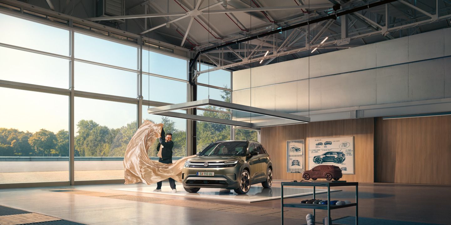 Moški odstranjuje veliko rjuho z zelenega VW ID. Crossa, ki stoji v minimalistično opremljenem oblikovalskem studiu.