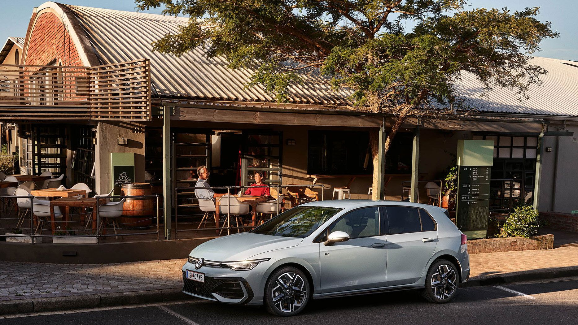 Der neue Golf GTE parkt an einem Straßenrand neben einem Café.