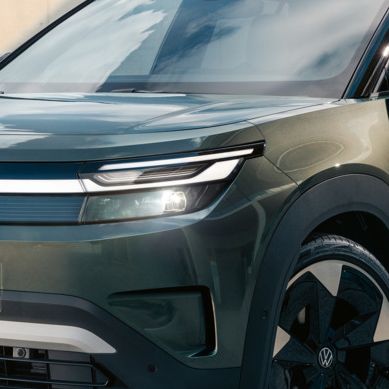 Zelen VW ID. Cross stoji na betonski površini pred sodobno stekleno stavbo.