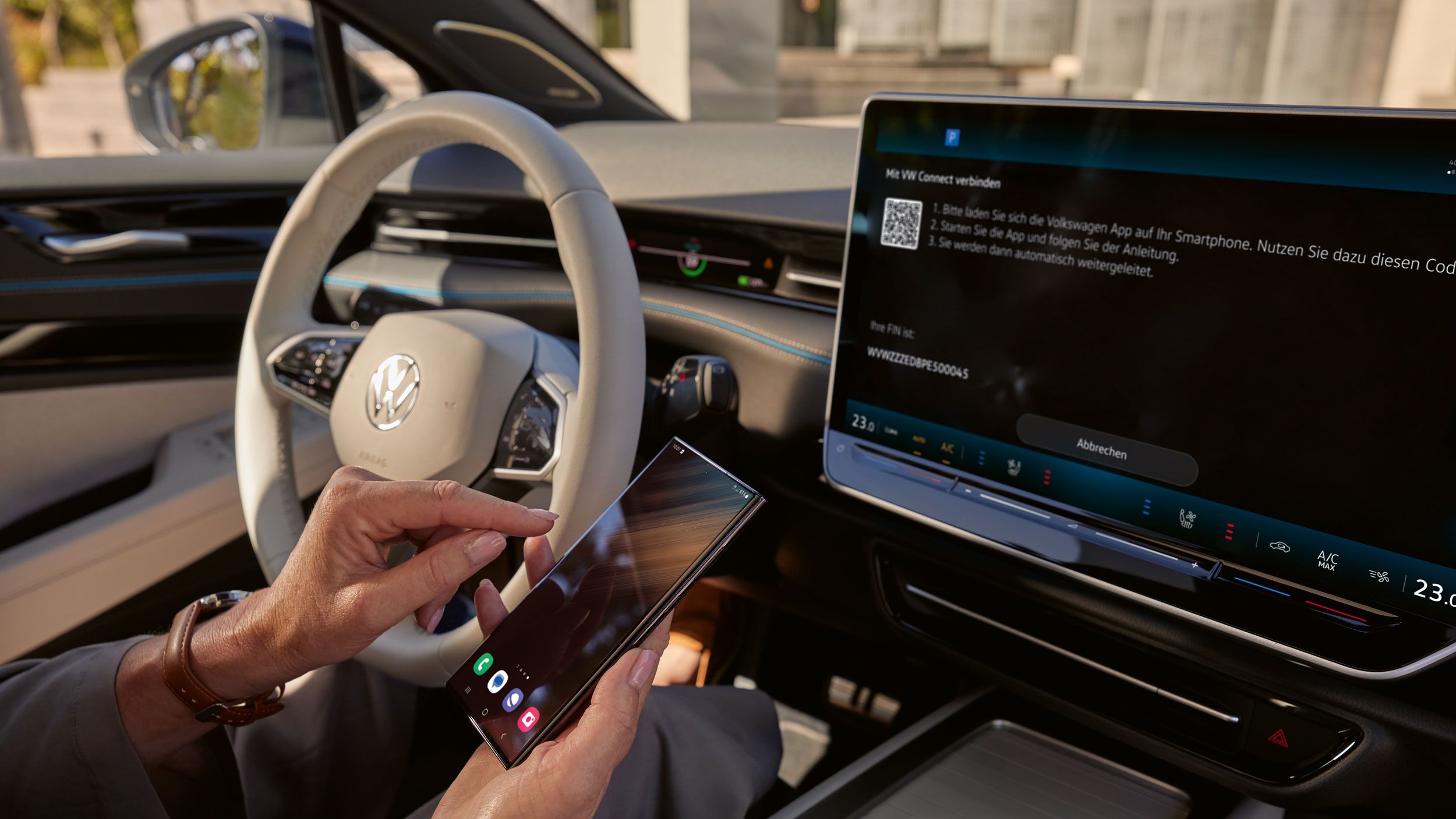 Pogled na armaturno ploščo v ID.7. Nekdo prek VW Connect povezuje pametni telefon z vozilom. Na zaslonu infotainment sistema je vidna povezava s VW Connect. 