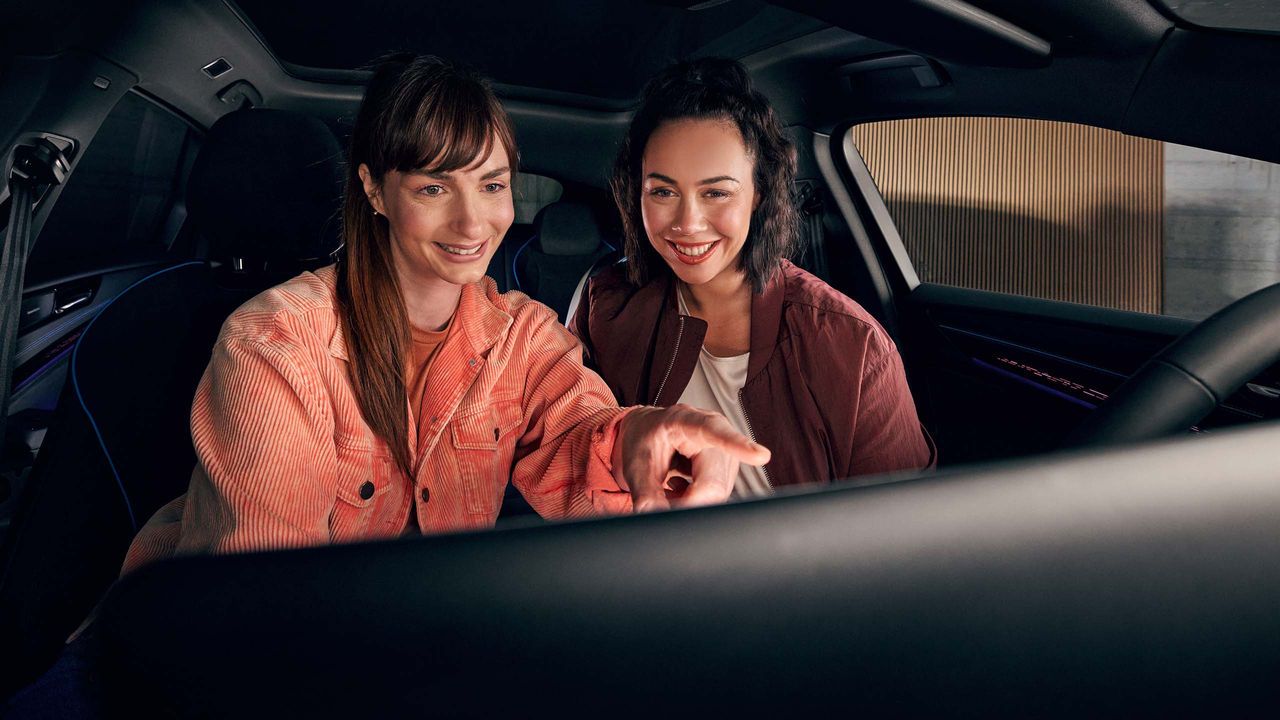 Zwei Frauen benutzen das Infotainment-System im VW Auto
